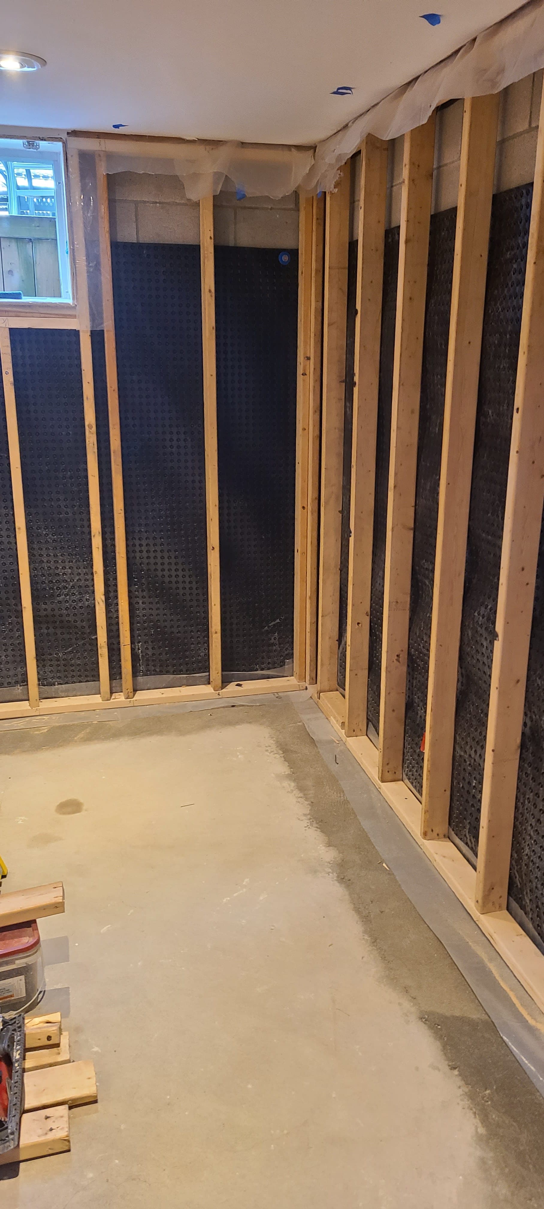 Basement framing — exposed studs and DMX dimple-board moisture barrier installed by Blue Tile & Marble
